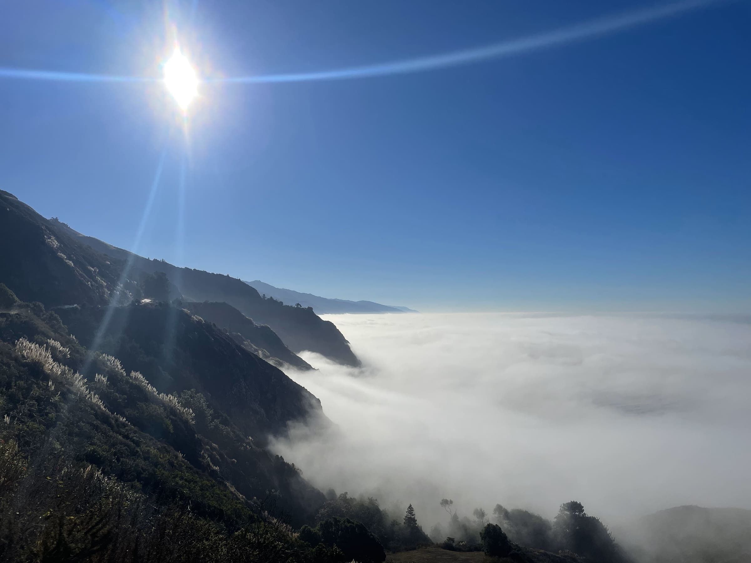 Sunlight breaking over a fog-covered coastal mountain ridge
